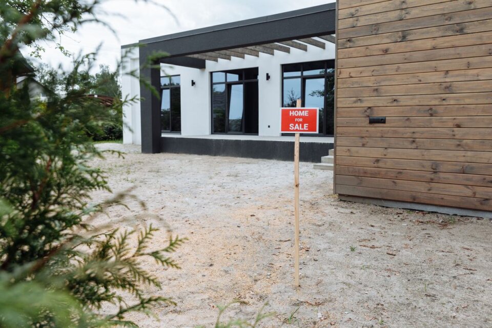 Maison moderne à vendre, avec un panneau dans le jardin, pour illustrer la plus-value immobilière