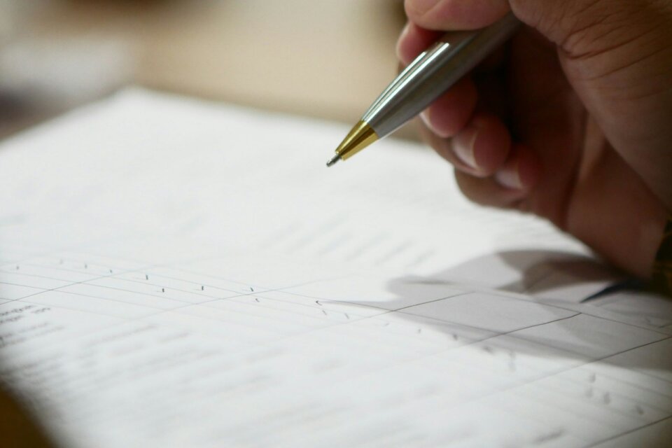 Main tenant un stylo au-dessus d’un compromis de vente à signer