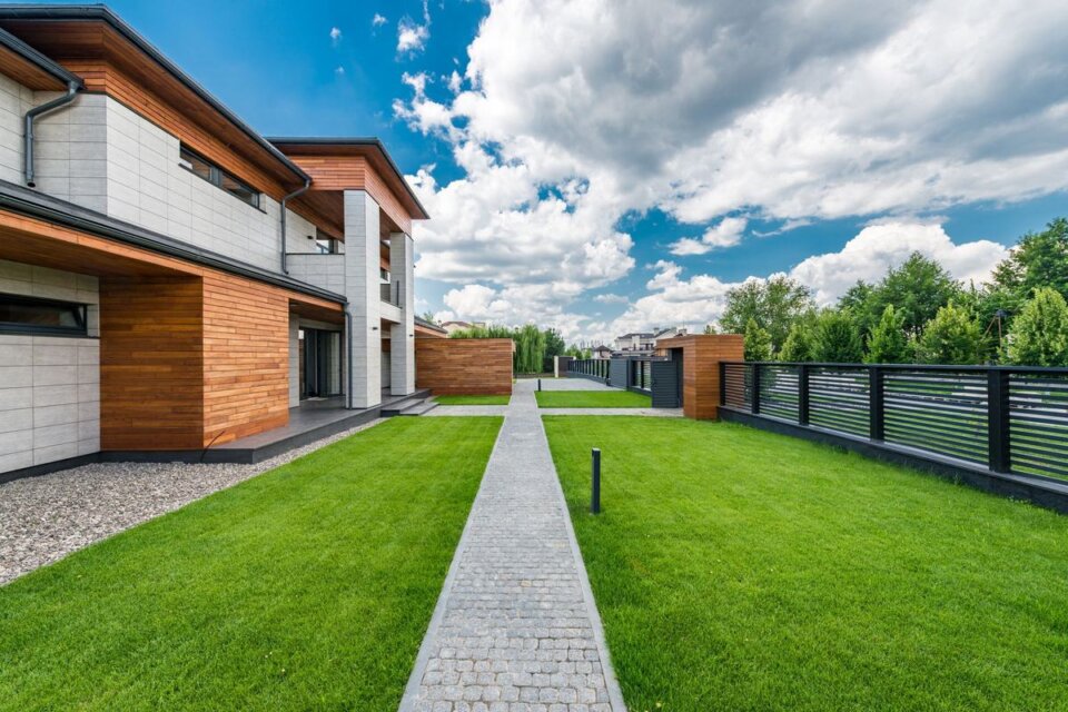 Vendre sa maison : maison moderne avec façade en bois, jardin et allée pavée sous un ciel bleu
